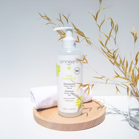 Photo of Tonic Tea Shampoo on a wooden tray with a towel and a plant